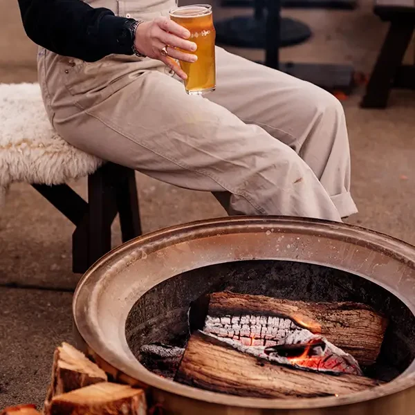 person-holding-beer-by-firepit person hold beer by the firepit