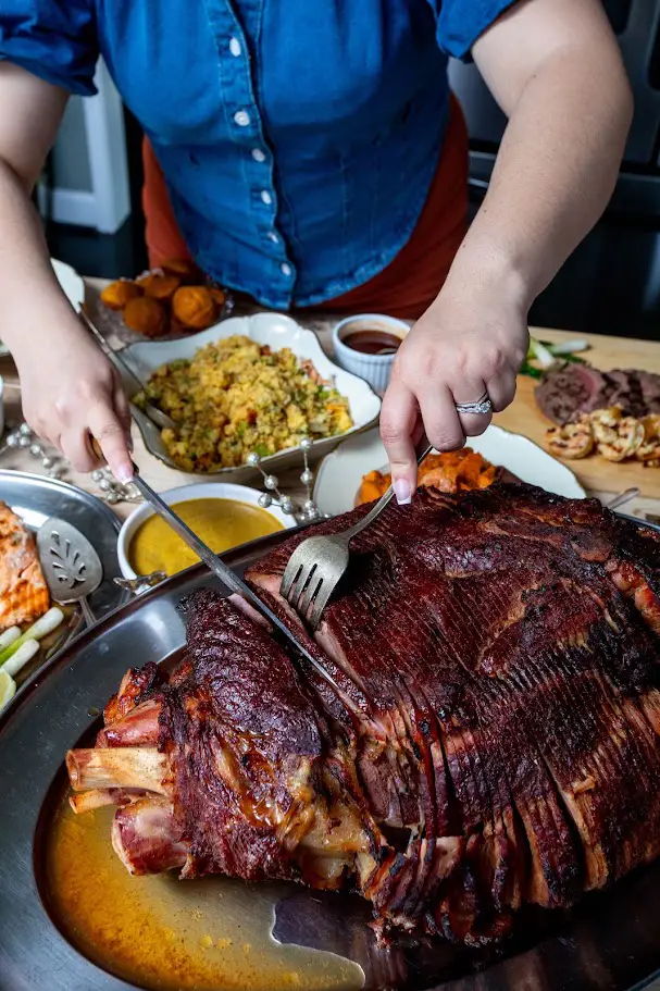 Person cutting large smoked ham