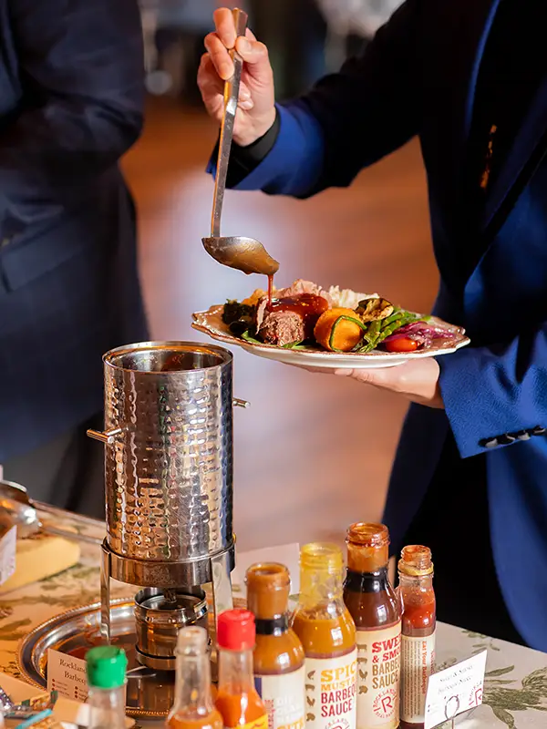 Guest spooning Rocklands sauce on to plate